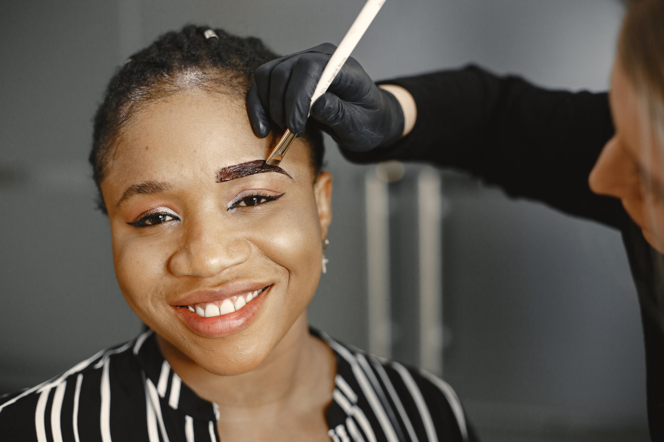 Woman Painting Eyebrows with a Brush in Black Gloves